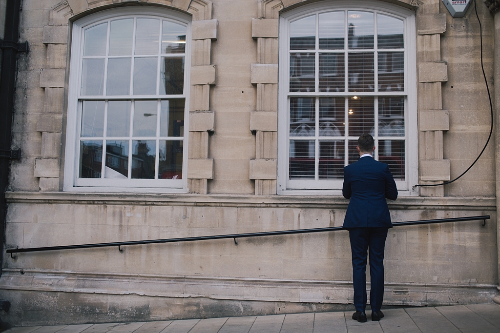 Groom checking himself in window before the wedding ceremony at Battersea Arts Centre by Lisa Jane Photography