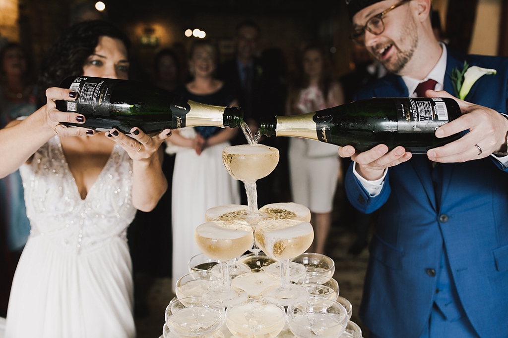 Couple pouring champagne for the champagne tower at their Wiltons Music Hall Wedding