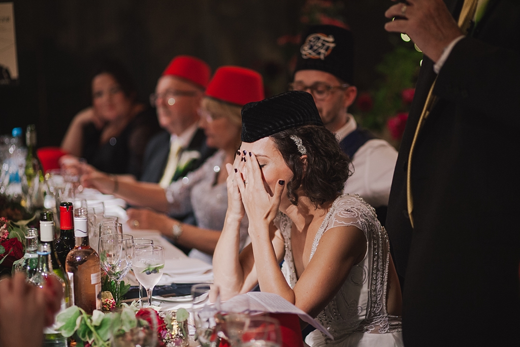 bride holding her head as dad embarrass' her during father of the bride speech
