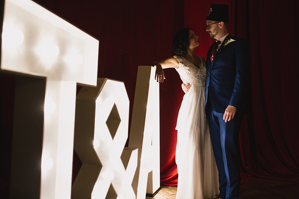 bride & groom stood next to their initials in giant light up letters 