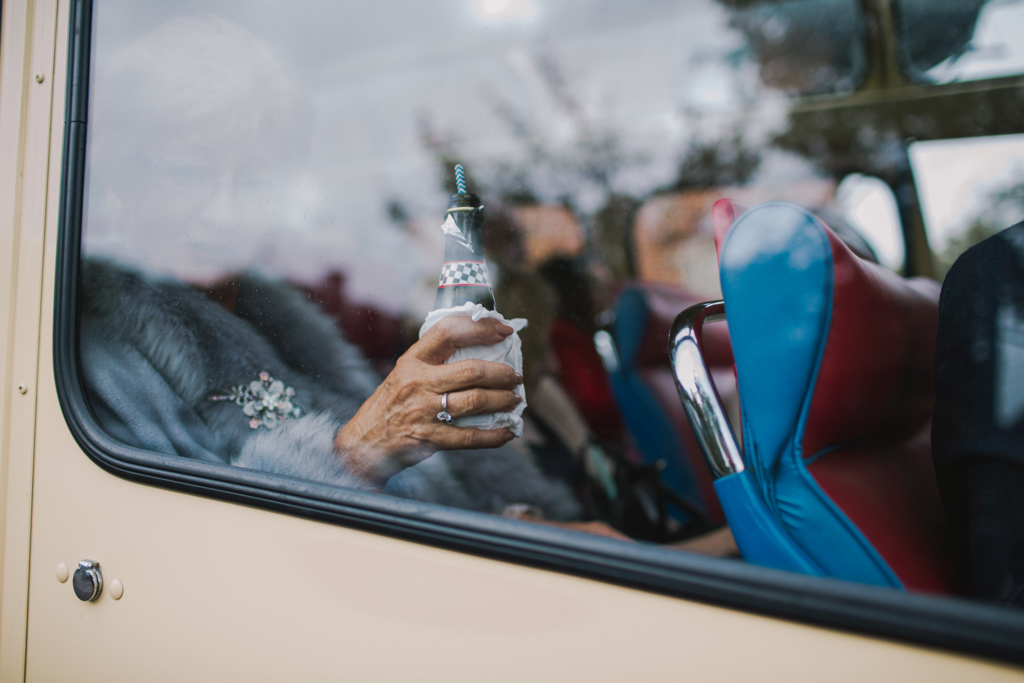guest holding a bottle of prosecco on a vintage bus | Lisa Jane Photography | Modern London Wedding Photography