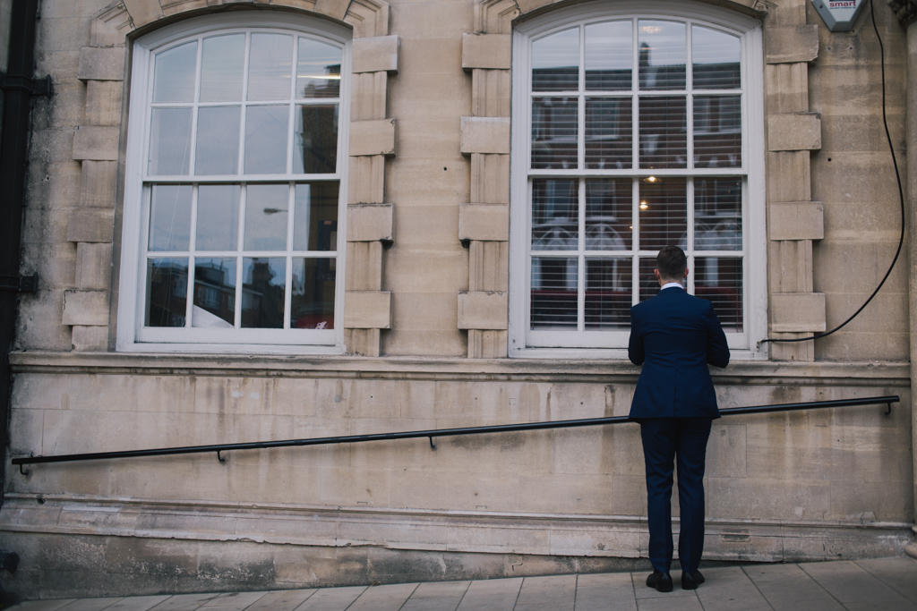 Groom checking himself in the window before his group shot at a Battersea Arts Centre wedding | Lisa Jane Photography | Modern London Wedding Photography